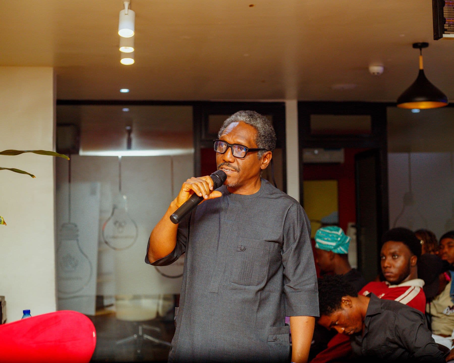 A speaker in glasses shares his experience with the audience